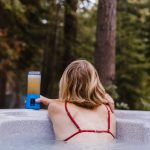 woman sitting in hot tub in backyard with drink